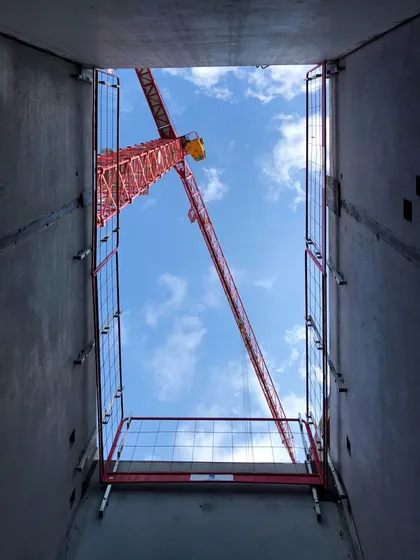 建設中の建物の吹き抜けから見上げたタワークレーン